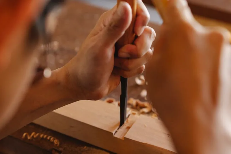 Hammer tapping a nail set under a door hinge barrel to push the pin upward